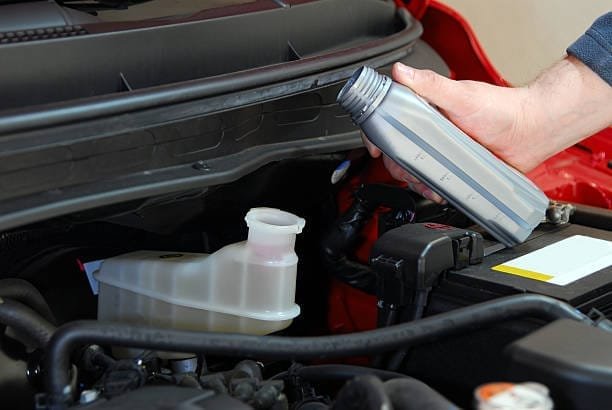 mechanic adds brake fluid to a Car